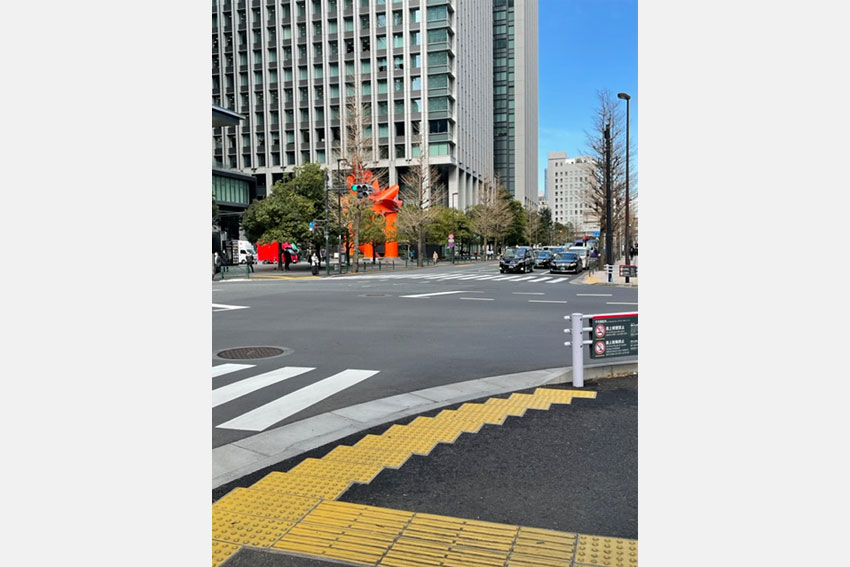 地下鉄大手町駅A4出口から地上に出て後方に、赤いモニュメントのある広場が見えます。